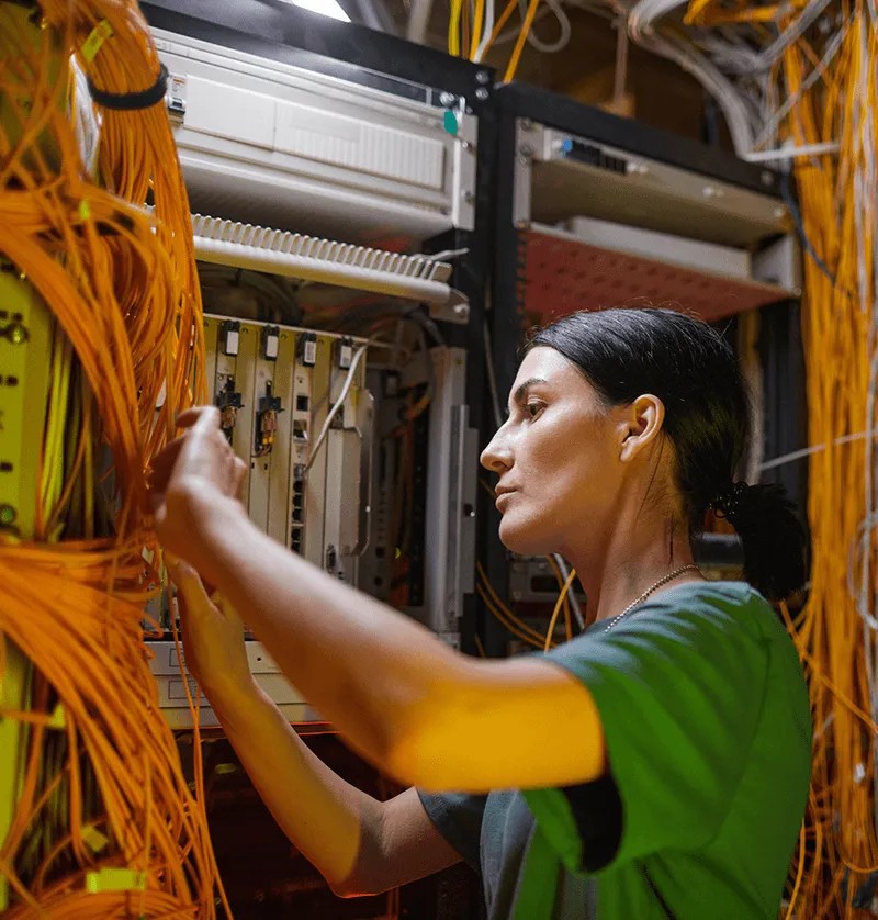 Technician working on an orange fibre-optic patch rack