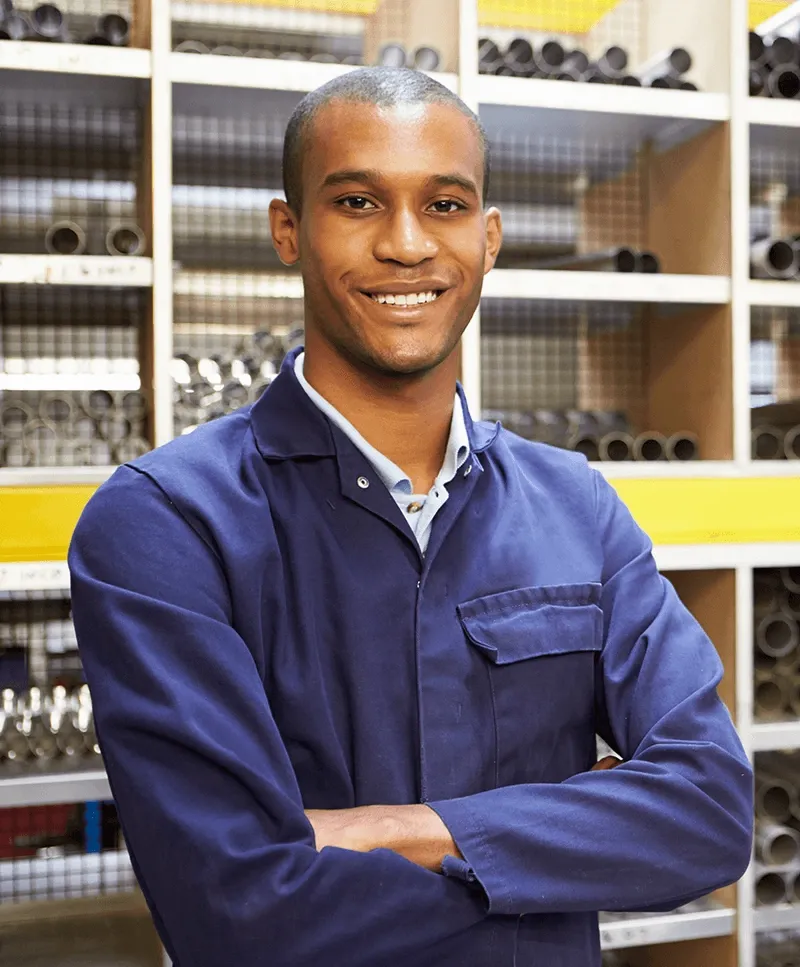 Tradesperson in work coveralls standing in a pipe supply warehouse